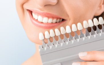 woman holding up veneers | Porcelain Veneers in Monroe MI | Kuras Dental Health Associates