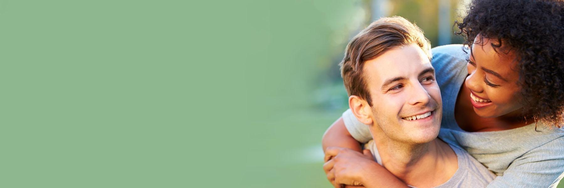 Young couple laughing & smiling outside l Dentist in Monroe MI